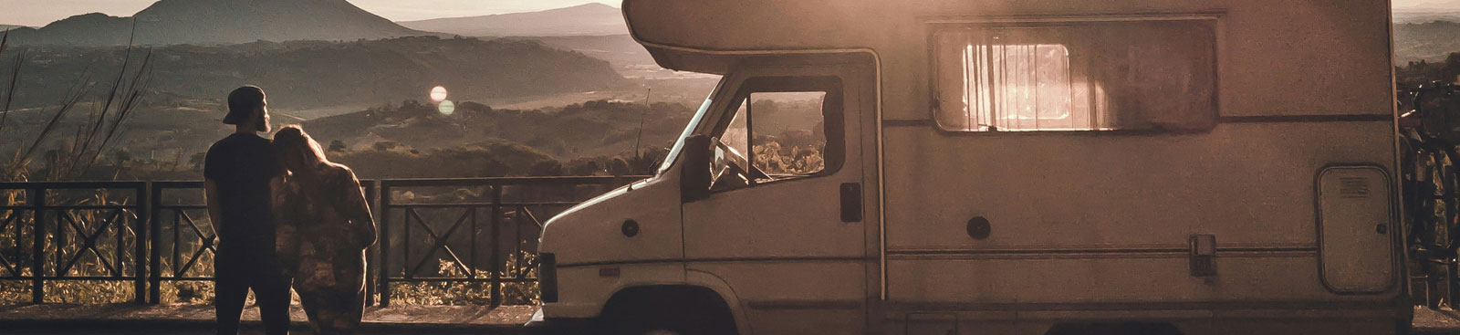 Paar vor einem Wohnmobil mit Blick auf eine Hügellandschaft