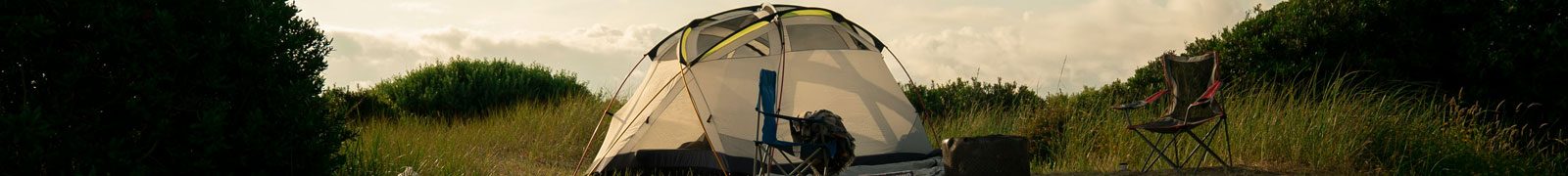 Kuppelzelt mit Campingstuhl zwischen Dünen