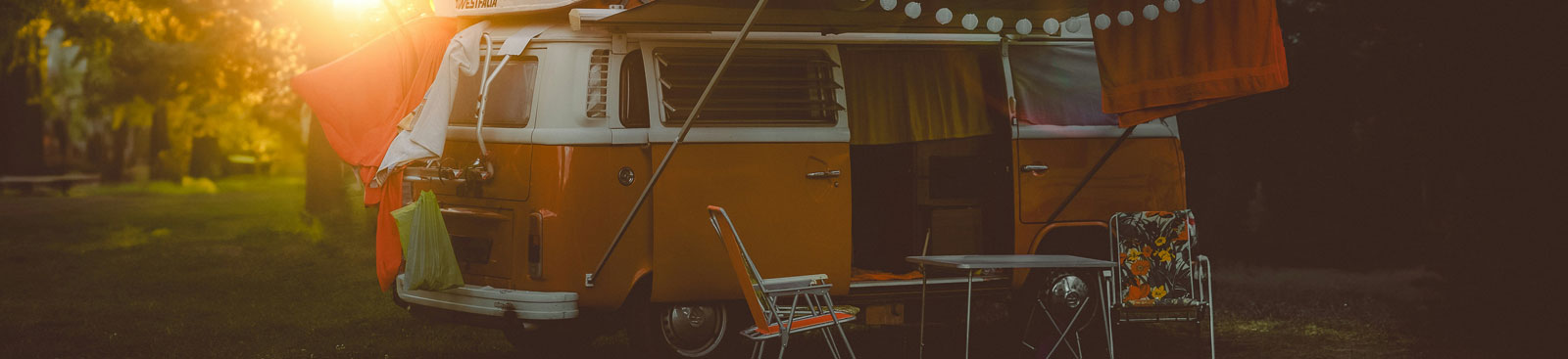 Klassischer Campingbus mit Klapptisch und Stühlen im Abendlicht
